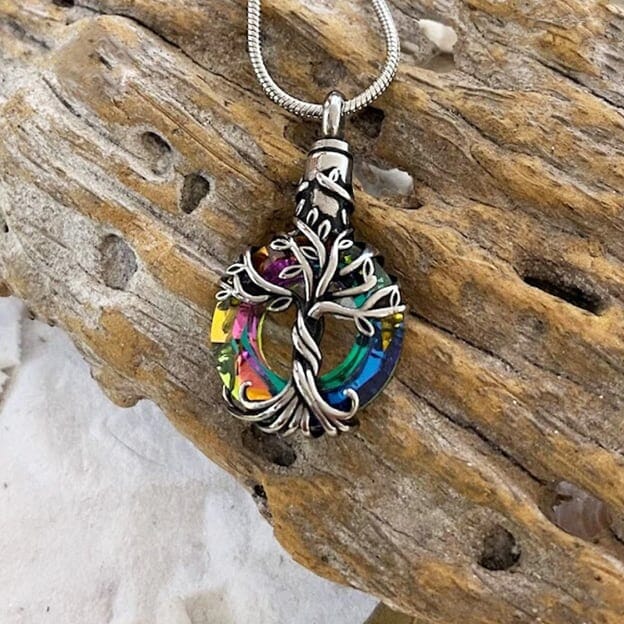 The Iridescent Cut Glass with Tree of Life Cremation pendant has the roots embracing a cut glass ring with shades of blue and green.