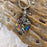 The Iridescent Cut Glass with Tree of Life Cremation pendant has the roots embracing a cut glass ring with shades of blue and green.