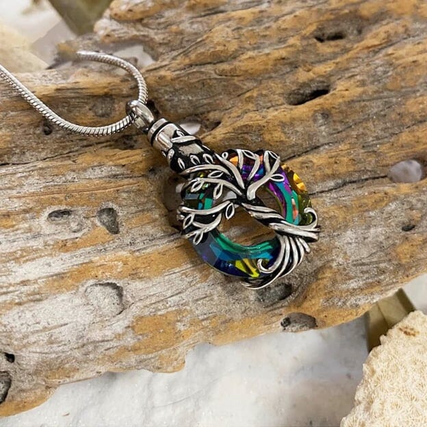 The Iridescent Cut Glass with Tree of Life Cremation pendant has the roots embracing a cut glass ring with shades of blue and green.